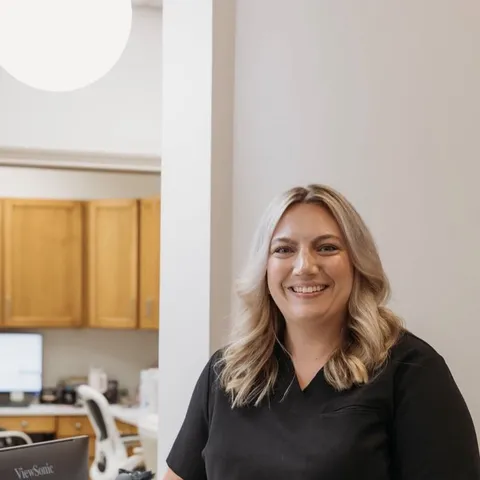 Kayla, a dental assistant at Cactus Pear Dental, smiling beside the front desk