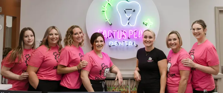 The Cactus Pear Dental team in matching pink shirts at the front desk