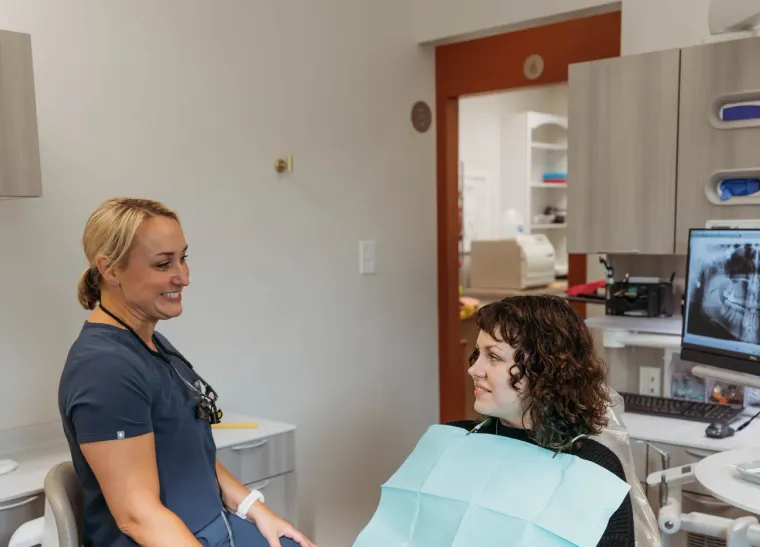 Dr. Kim Oberlander talking with a patient seated in the treatment chair